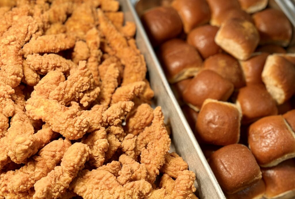 Crispy Chicken Tenders and rolls in serving pans.