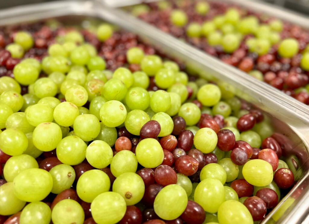 Grapes arranged in 4-inch half hotel pans for service.
