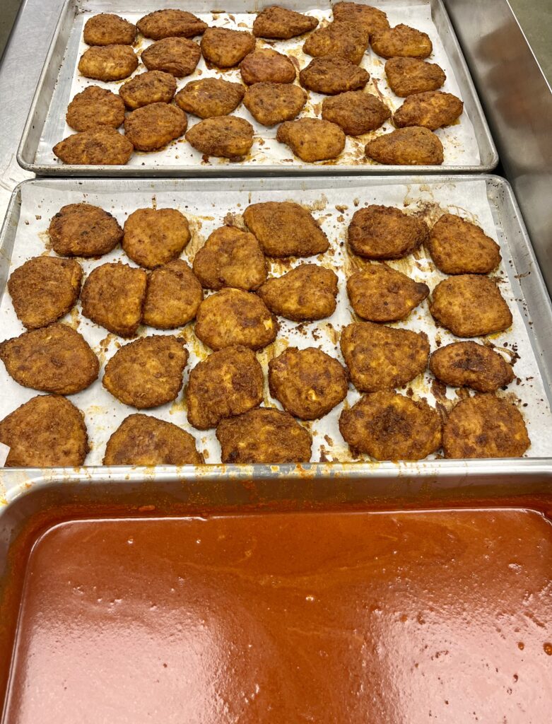 Dipping chicken filets in Nashville hot sauce.