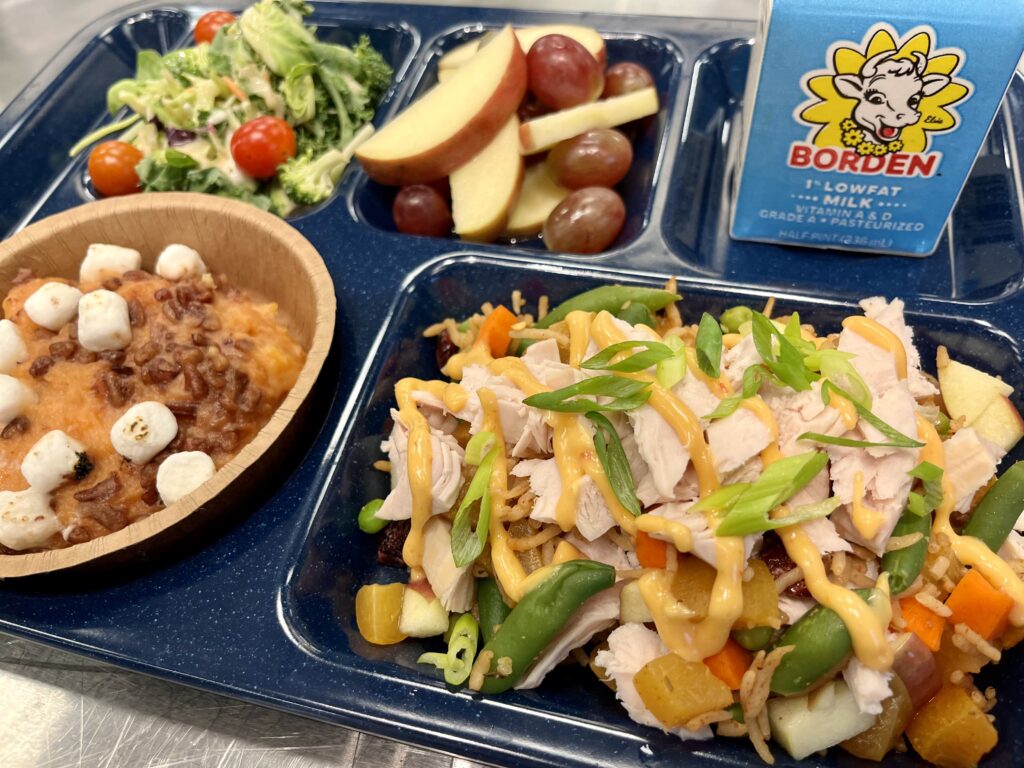 School lunch tray with Harvest Fried Rice, sweet potato casserole, fresh fruit, salad and milk.