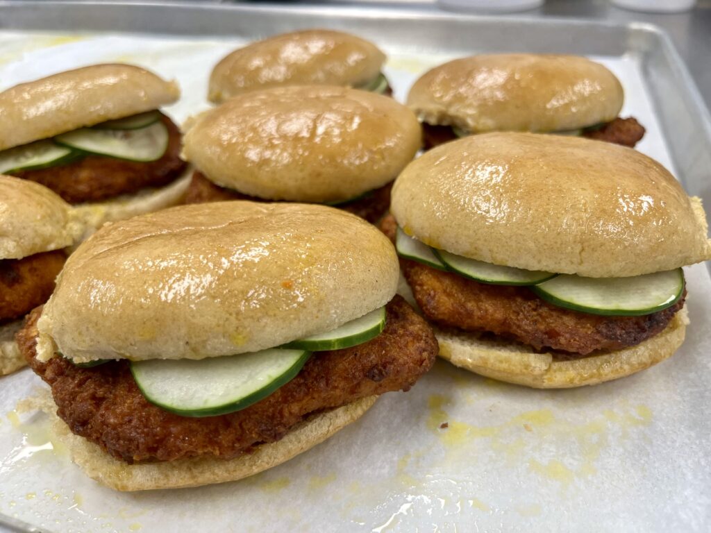 Nashville Hot Chicken Sandwiches with Housemade Pickles on a pan.