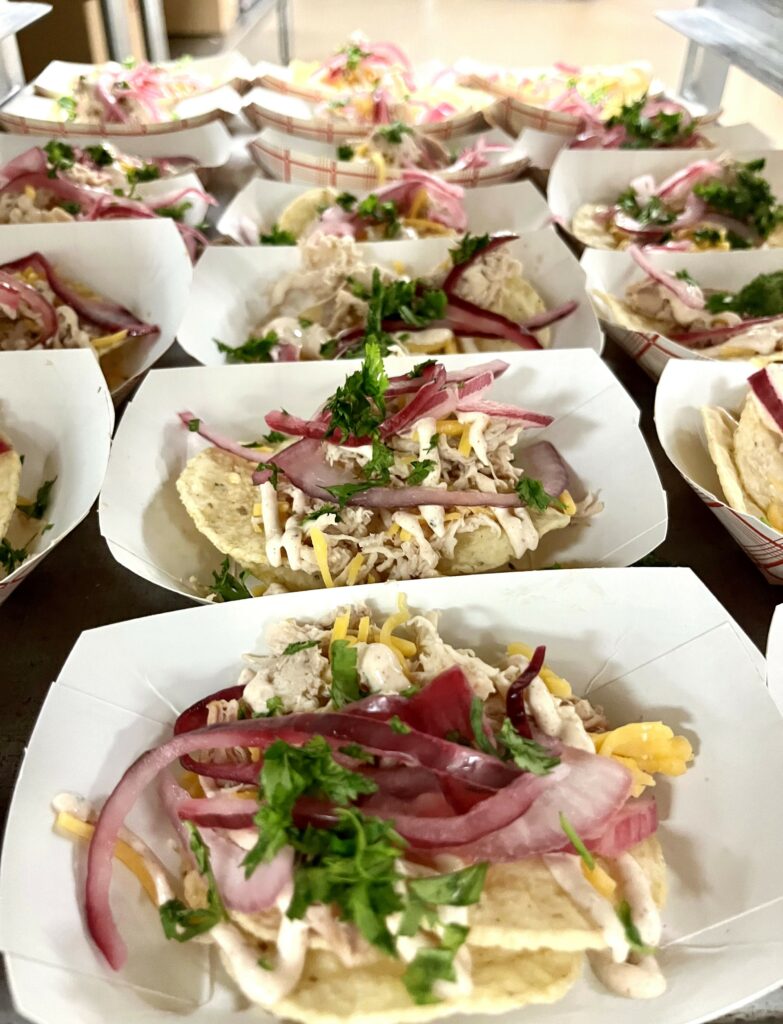 BBQ Chicken Nachos with Alabama White Sauce in paper serving boats.