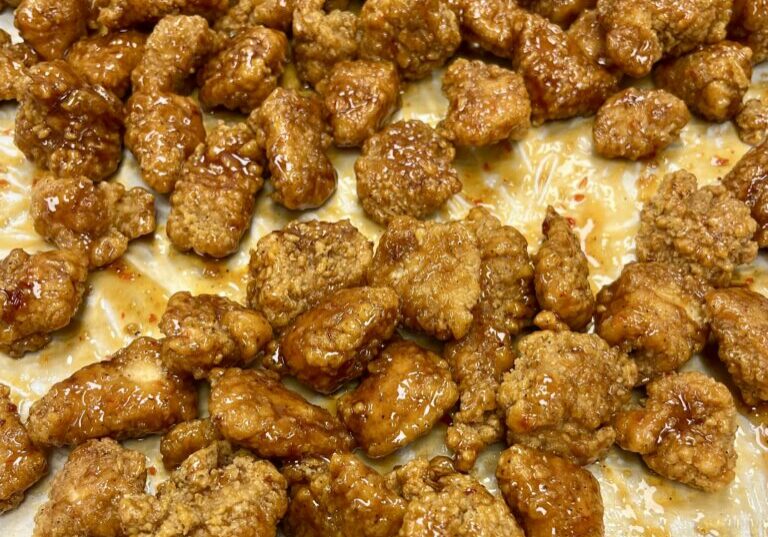 Chicken tossed in orange glaze on pan.