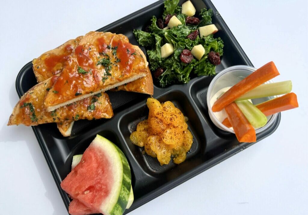 School lunch tray with Sweet and Spicy PBJ, kale salad, fresh fruit and veggie dippers in ranch dressing.